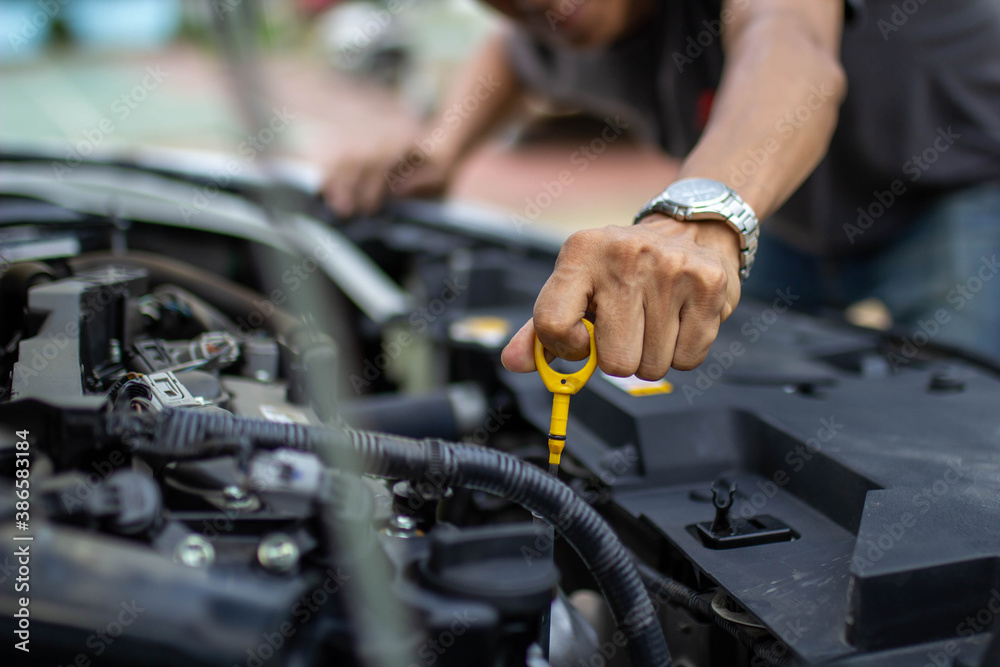 Auto repair center, an auto mechanics hand, is checking the engine oil level so the car is ready to