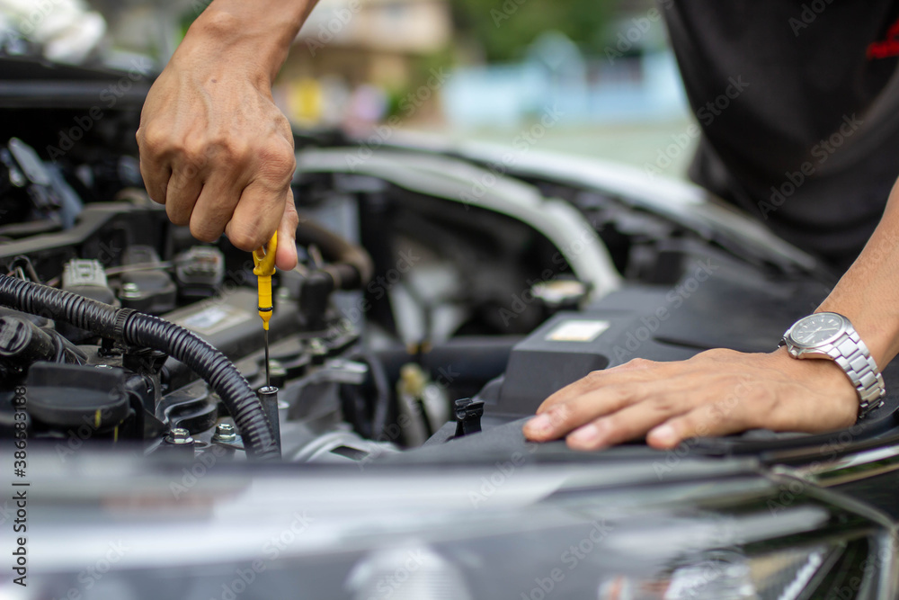 Auto repair center, an auto mechanics hand, is checking the engine oil level so the car is ready to