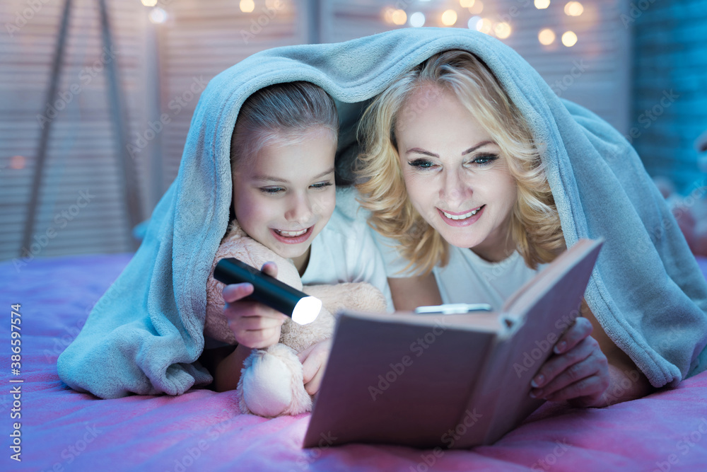 Grandmother with granddaughter reads a book.