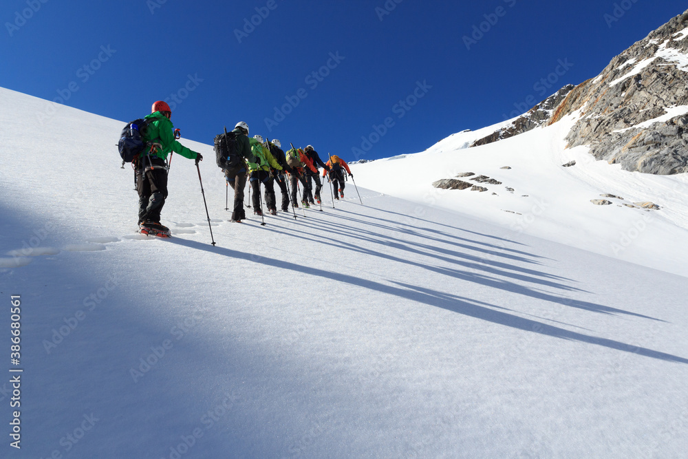 Rope team mountaineering with crampons on glacier Sexegertenferner towards Sexegertenspitze and moun