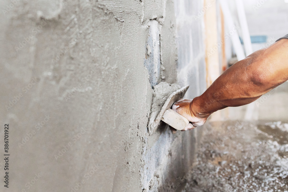 closeup hand of worker plastering cement at wall in construction site