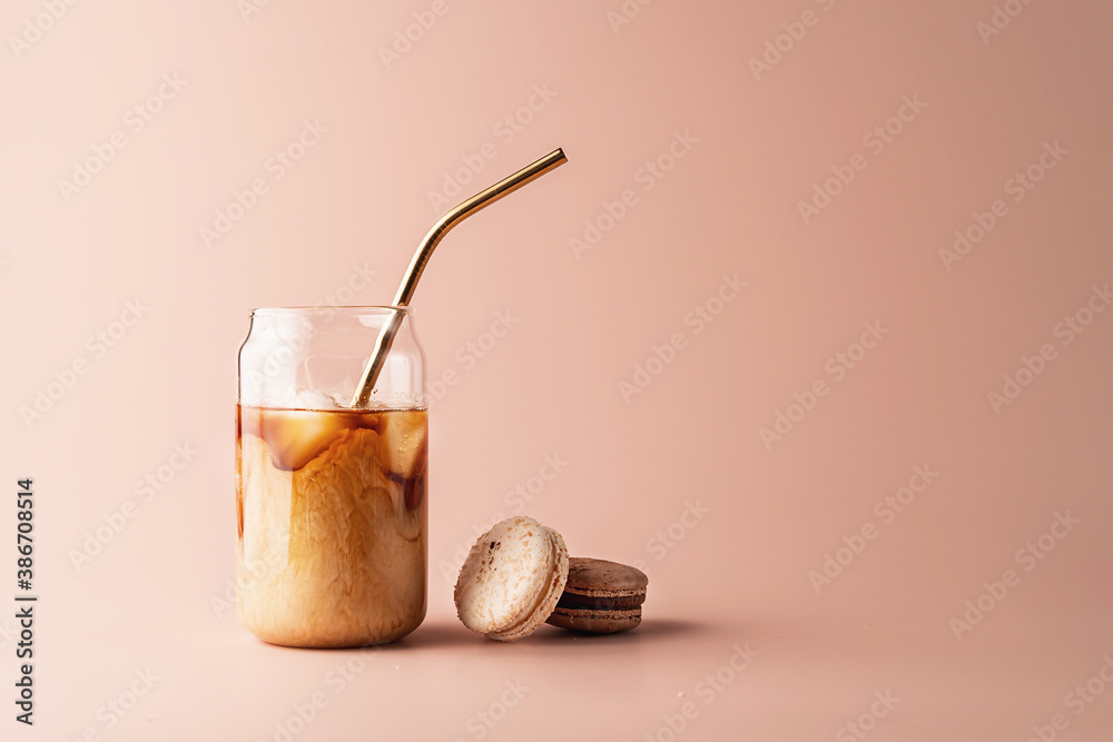 Glass of iced coffee in tall glass with golden straw with cream and macaroons chocolate, vanilla on 