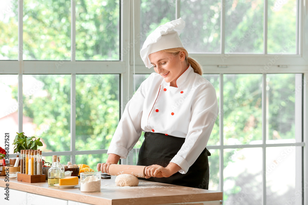 Female chef making dough in kitchen