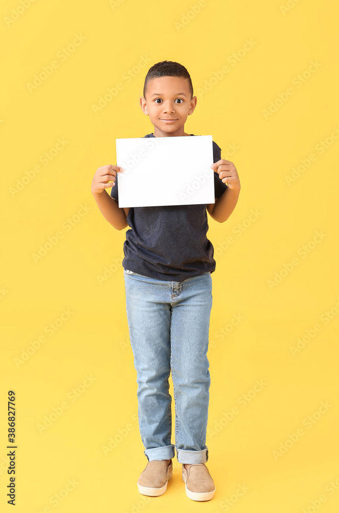 Little African-American boy with blank paper sheet on color background