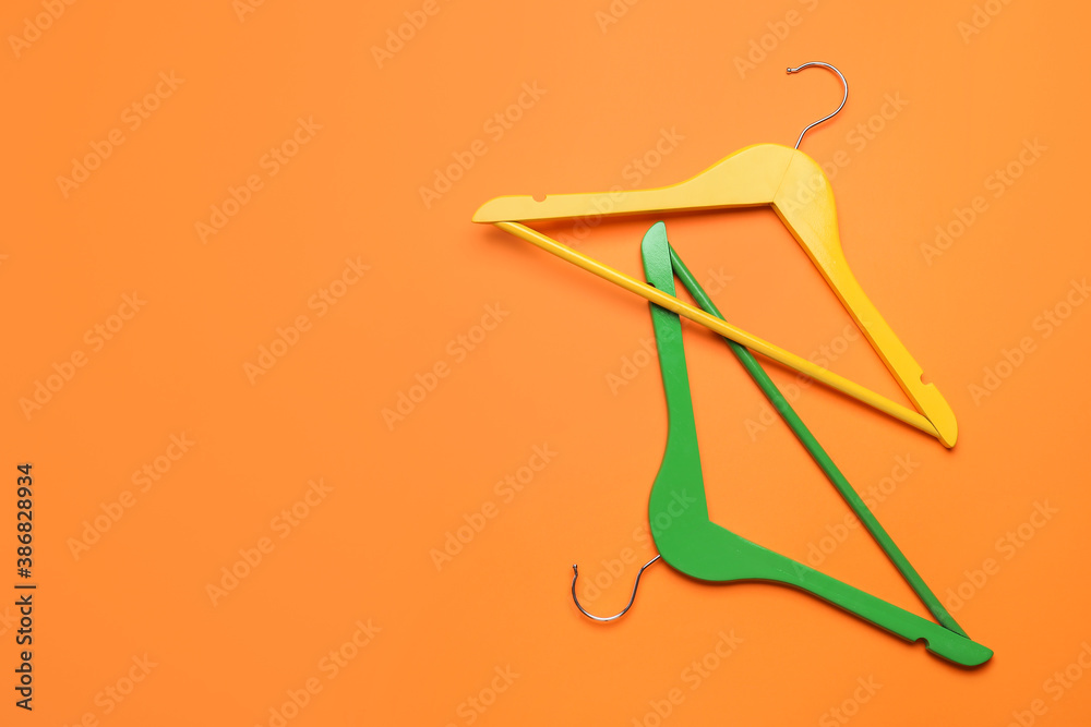 Clothes hangers on color background