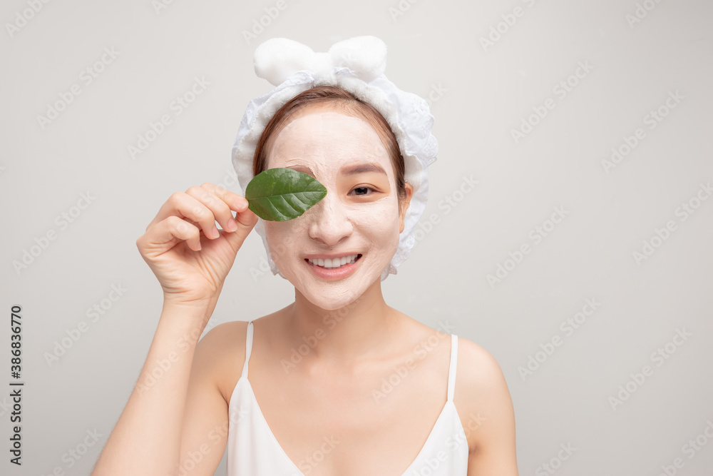 a smiling girl with a white towel on her head applied a clay moisturizing mask