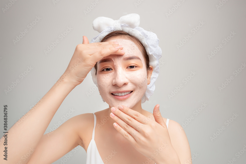 Portrait of confident lady in bathrobe and towel on head with joy while touching her face with clay 