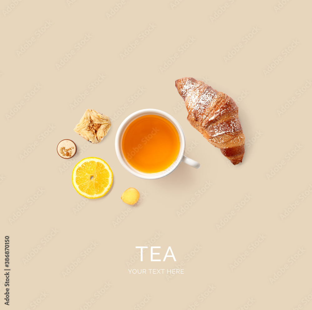 Creative layout made of tea, croissant and lemon on the beige background. Flat lay. Food concept.