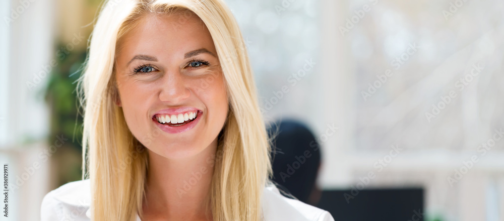 Happy young woman sitting at her desk in front of the computer