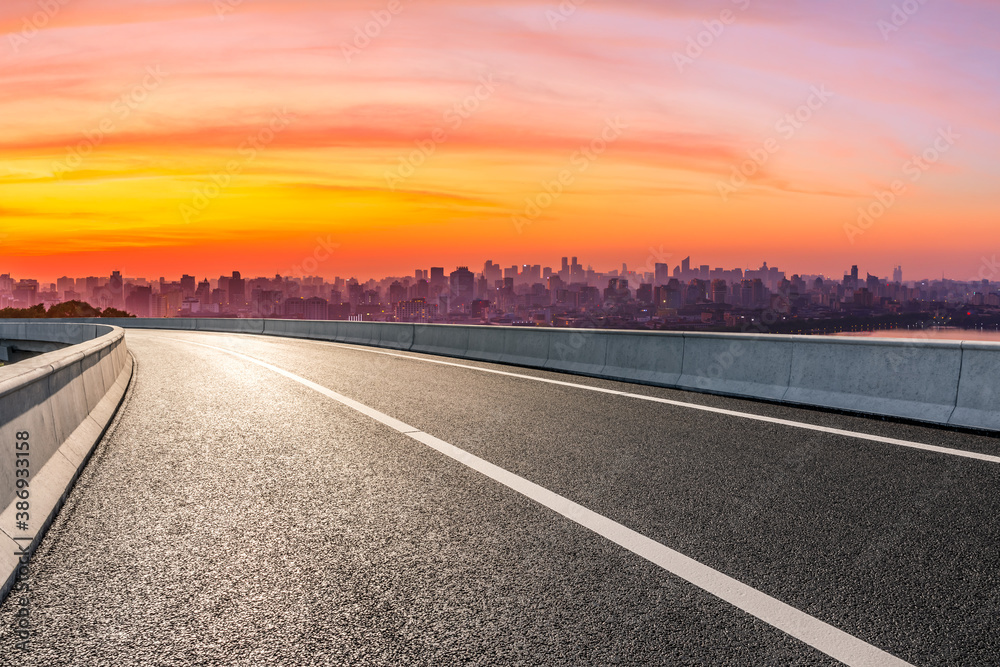 Empty asphalt road and city skyline with buildings in Hangzhou at sunrise.