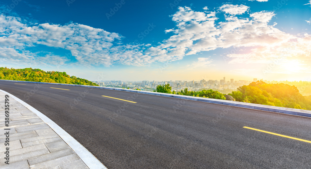 Asphalt road and city skyline with buildings in Hangzhou at sunrise.