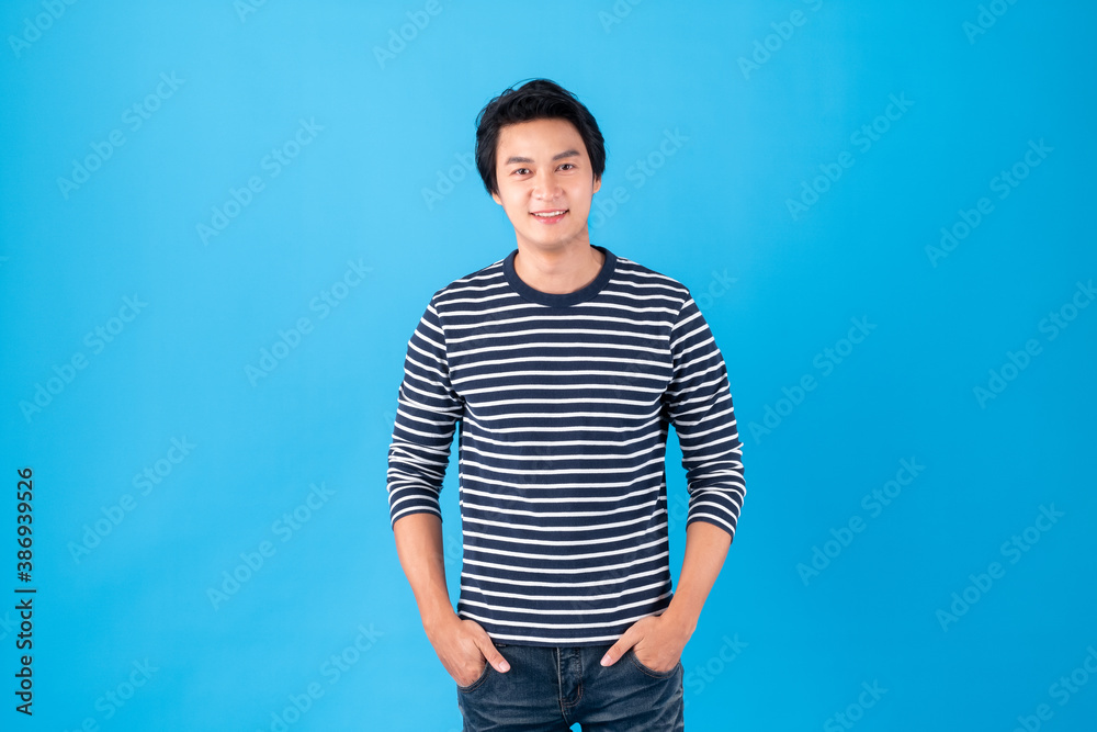 Portrait handsome young Asian man standing over blue background