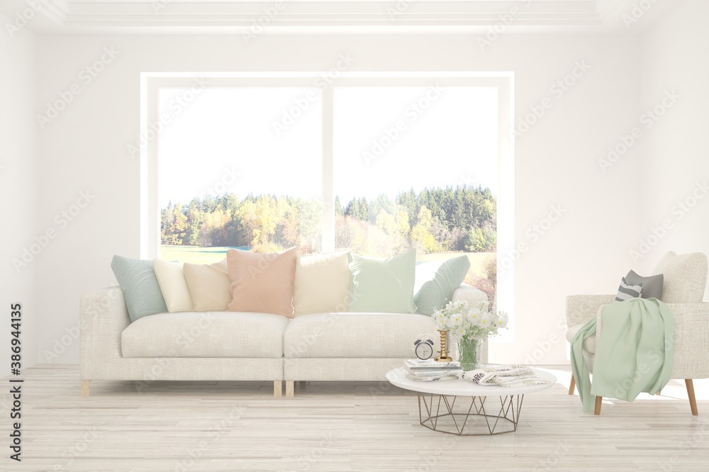 Stylish room in white color with sofa and autumn landscape in window. Scandinavian interior design. 