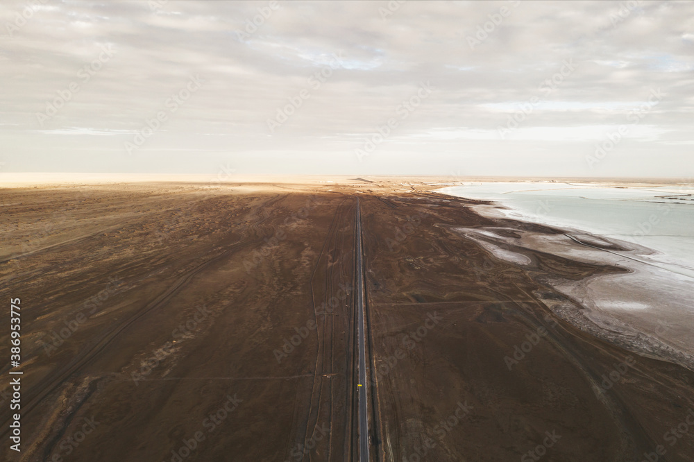 Straight road by the salt lake with wide flatlands background.