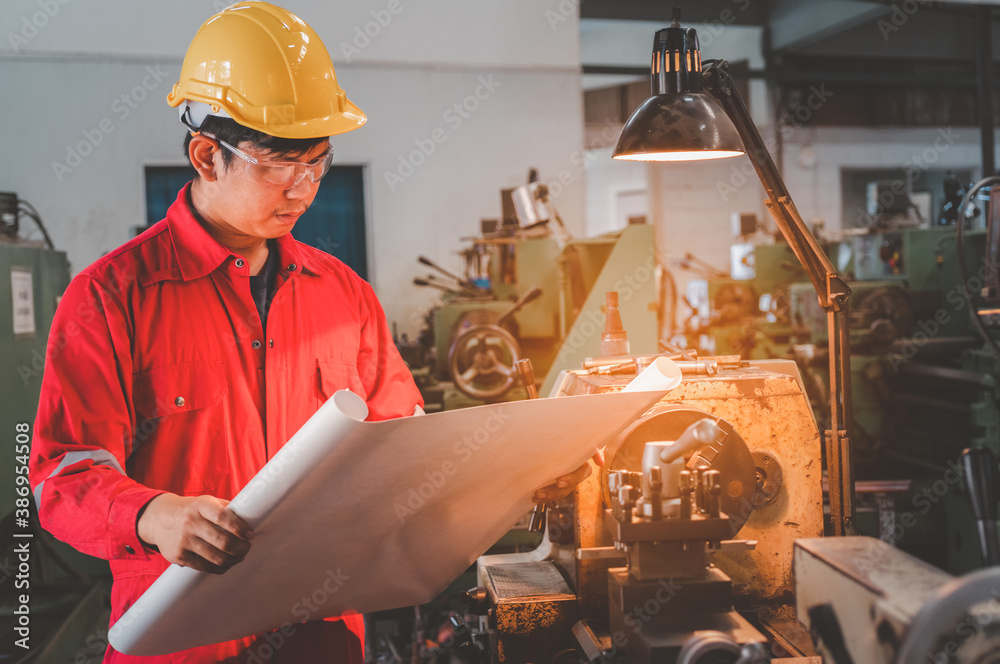 Asian man foreman working with drawing and NC Lathe machinery with safety uniform concept smart manu