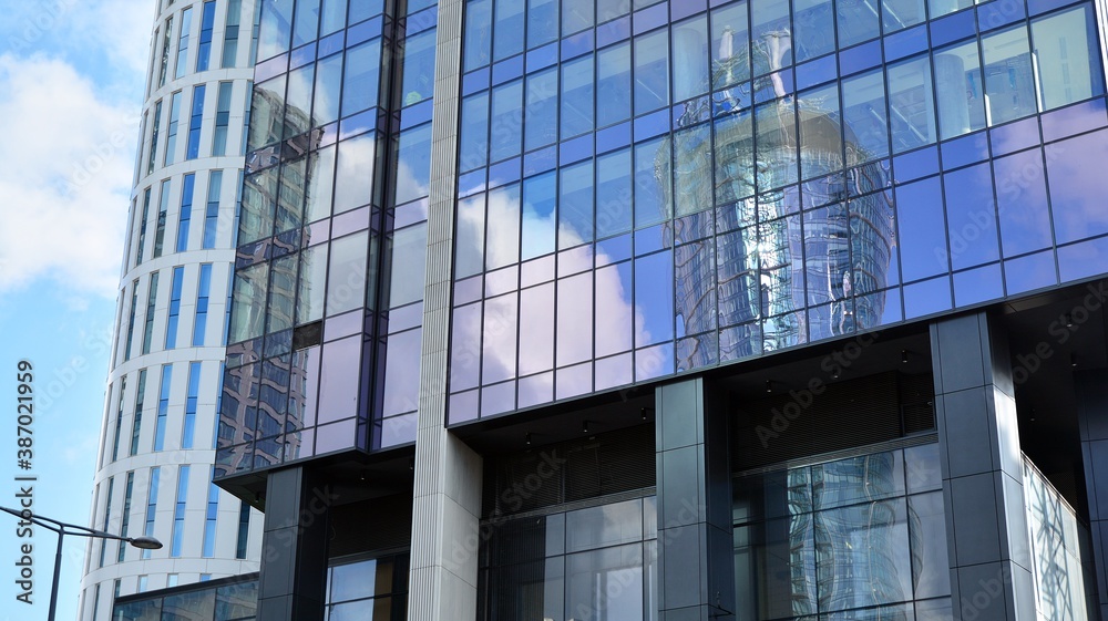 Blue curtain wall made of toned glass and steel constructions under blue sky. A fragment of a buildi