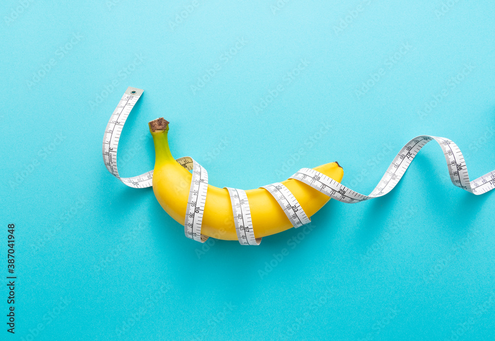 A banana with a measuring tape wrapped around a blue background