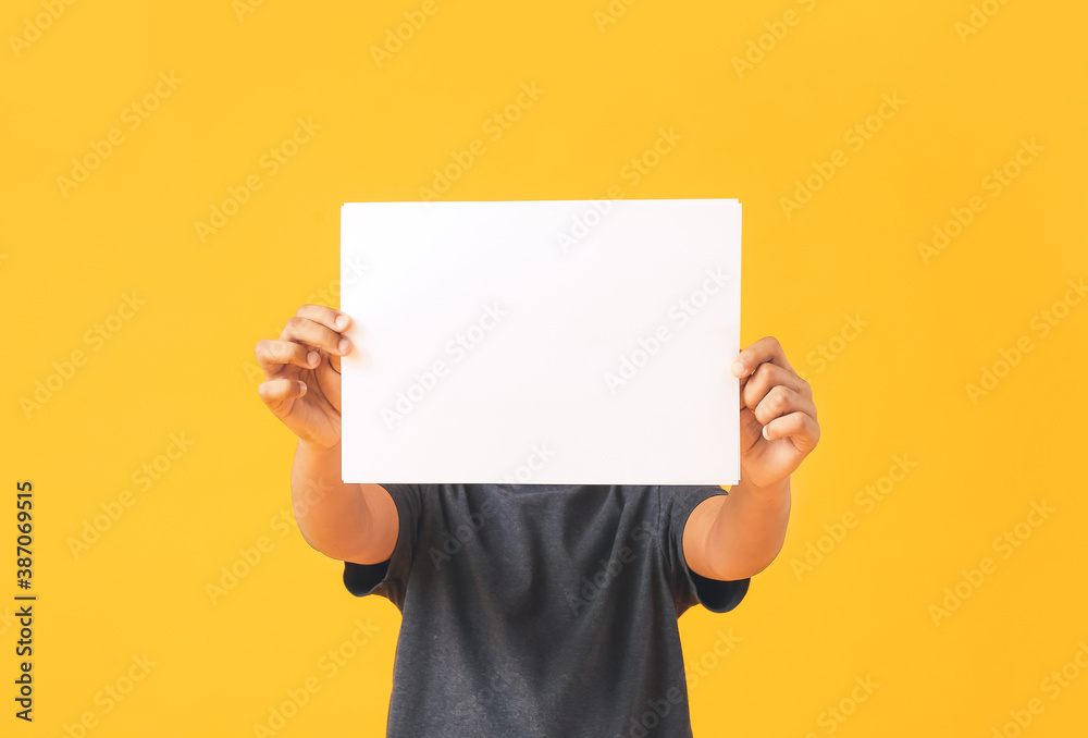 Little African-American boy with blank paper sheet on color background