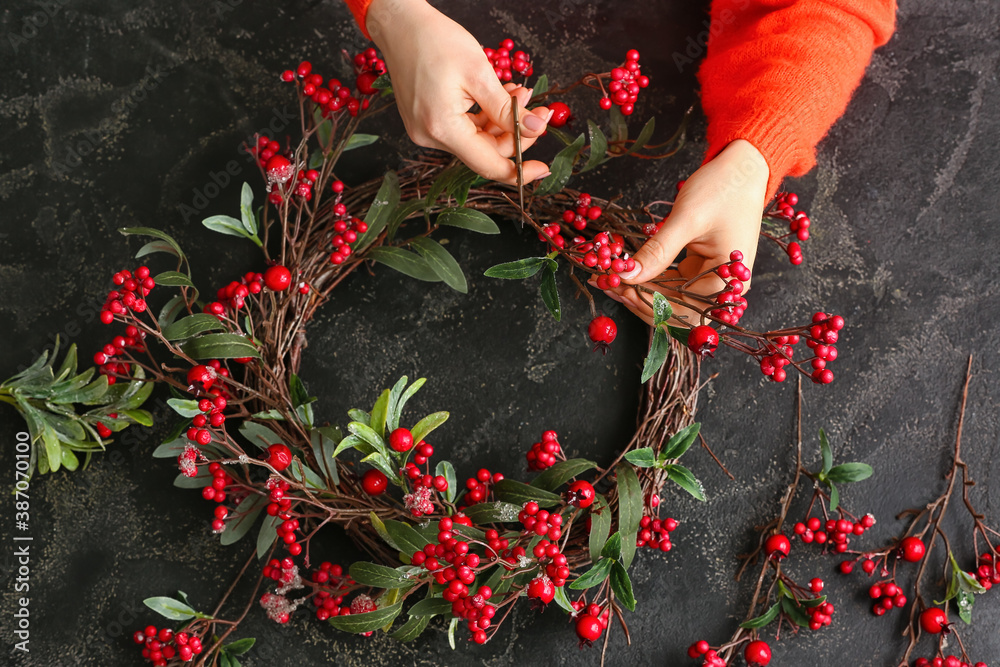 Woman making beautiful Christmas wreath at table