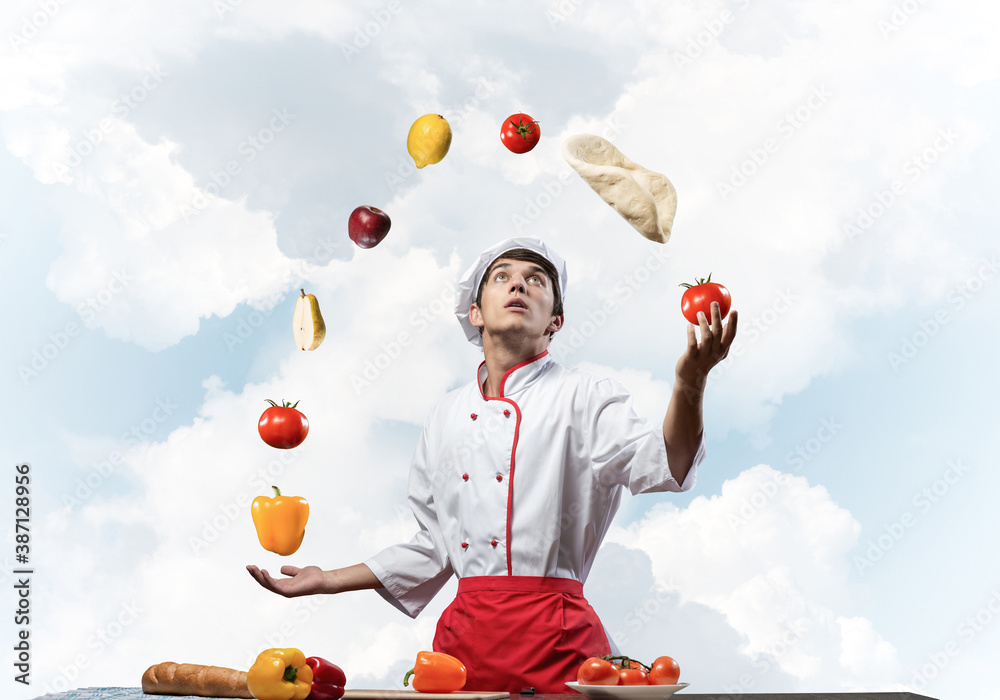 Young male chef juggles with food ingredients