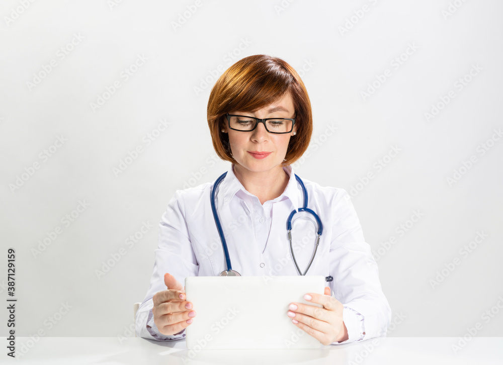 Redhead doctor using tablet computer in office