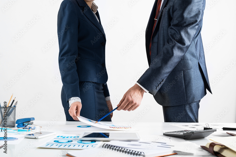 Businessman and businesswoman stand near desk