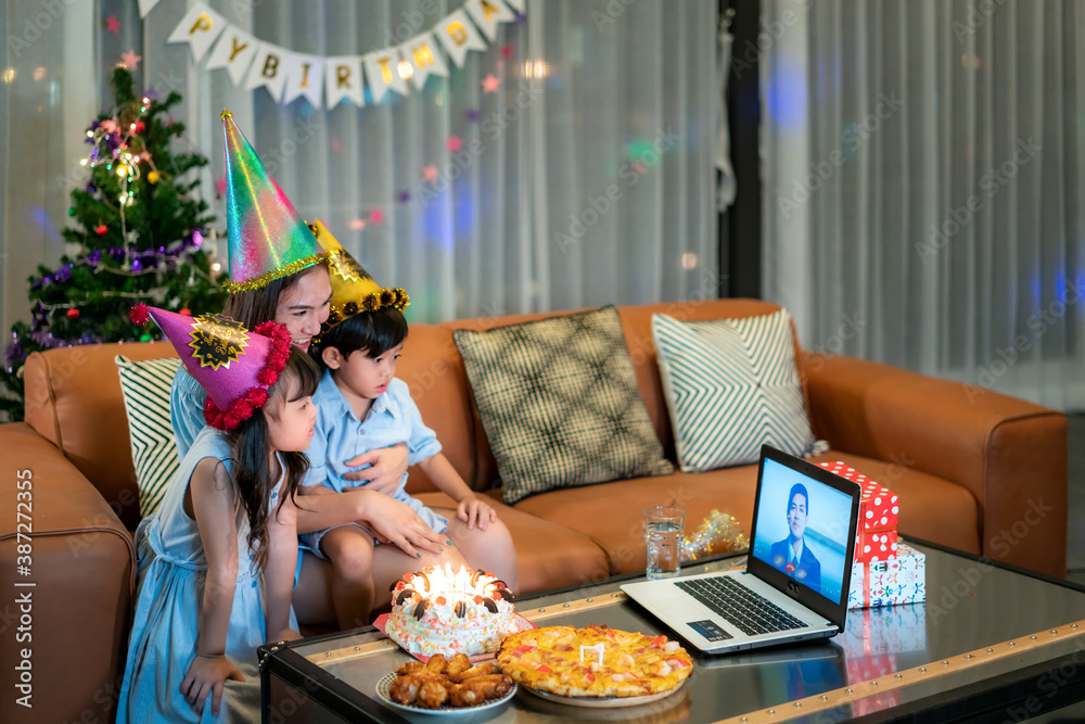 Happy girl and son celebrating birthday with her mother at home with father on video call in laptop 