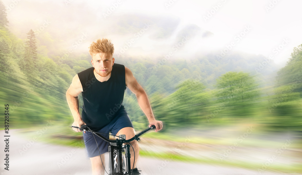 Young man riding bicycle in countryside