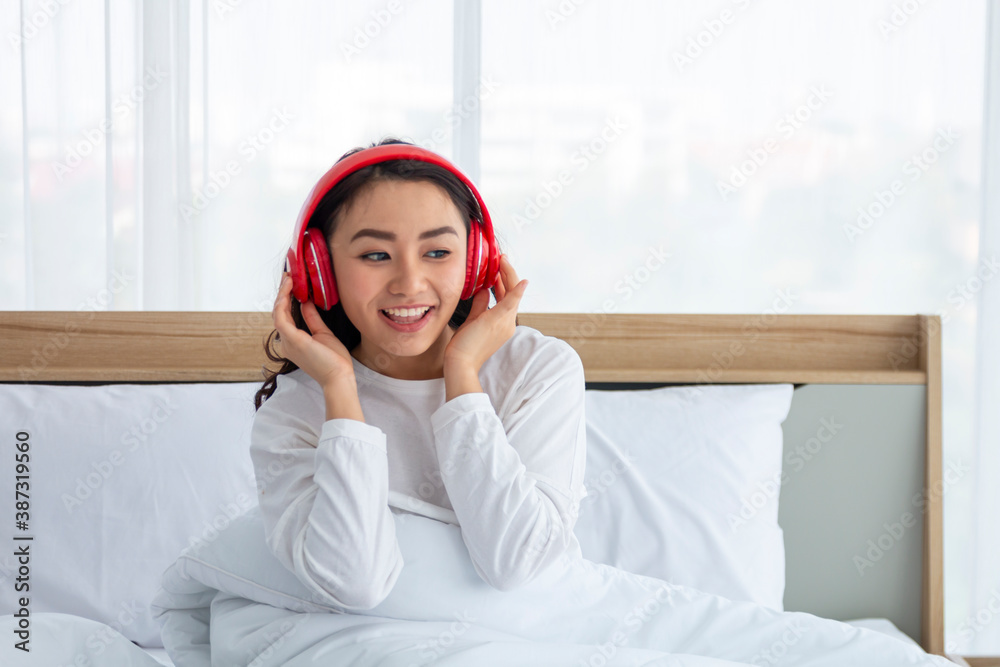 Happy woman female girl listening to music using headphones and smartphone on bed. Young woman or Te