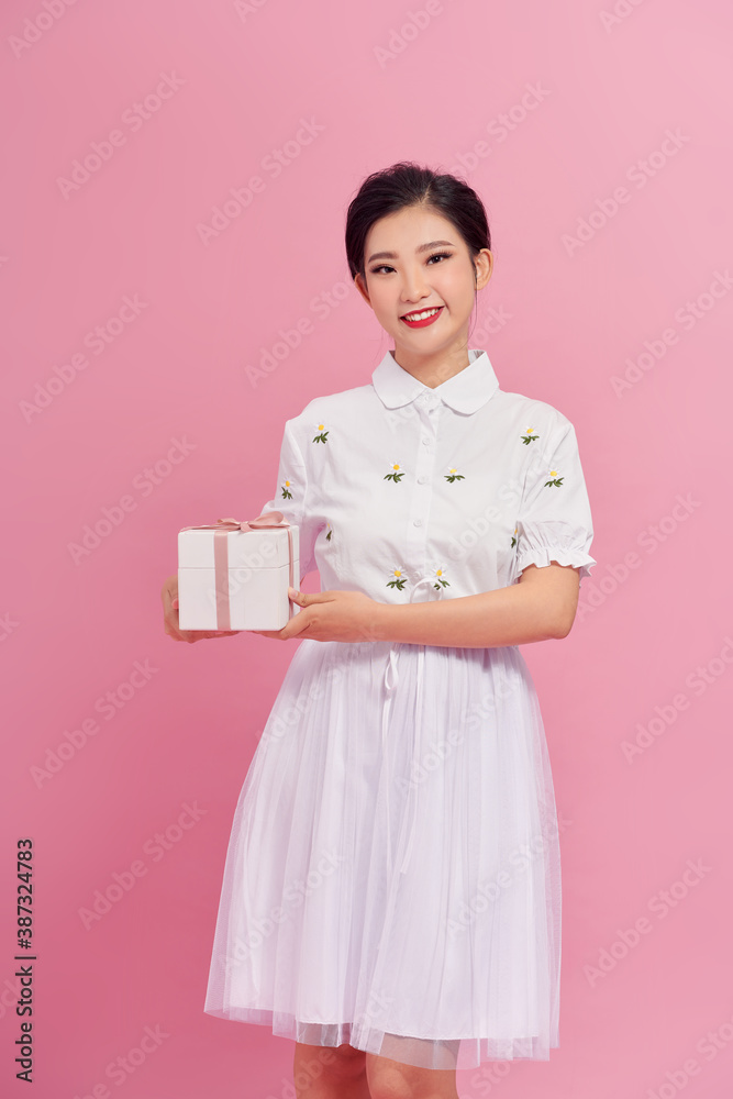 Picture of happy asian girl child standing isolated over pink background. Looking camera holding gif