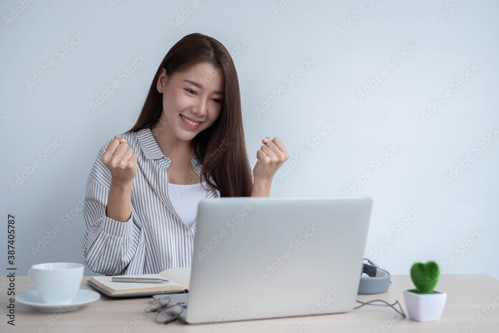 Portrait of a happy face Asian woman sitting at home working on a laptop while sitting on a desk. To