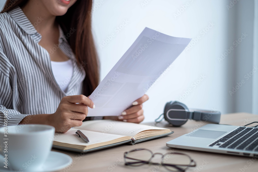 A business woman sitting on a computer desk holding a paper plan, business plan, work from home conc