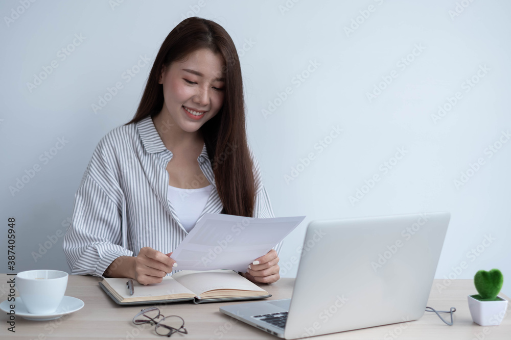 A business woman sitting on a computer desk holding a paper plan, business plan, work from home conc