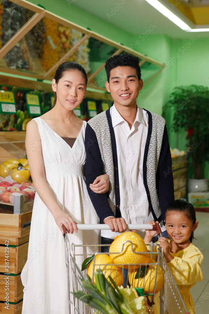 A happy family of three in the supermarket shopping