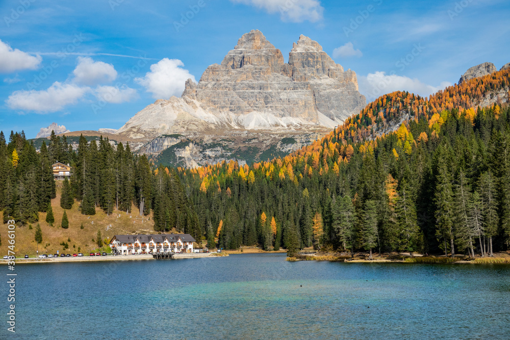 Scenic view of a mountain towering over colorful forest and calm lakefront hotel