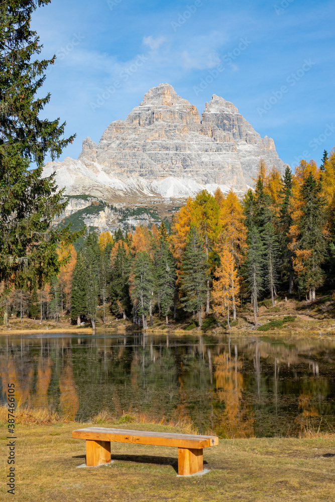 VERTICAL: Empty wooden bench faces the breathtaking Lago dAntorno and Dolomites