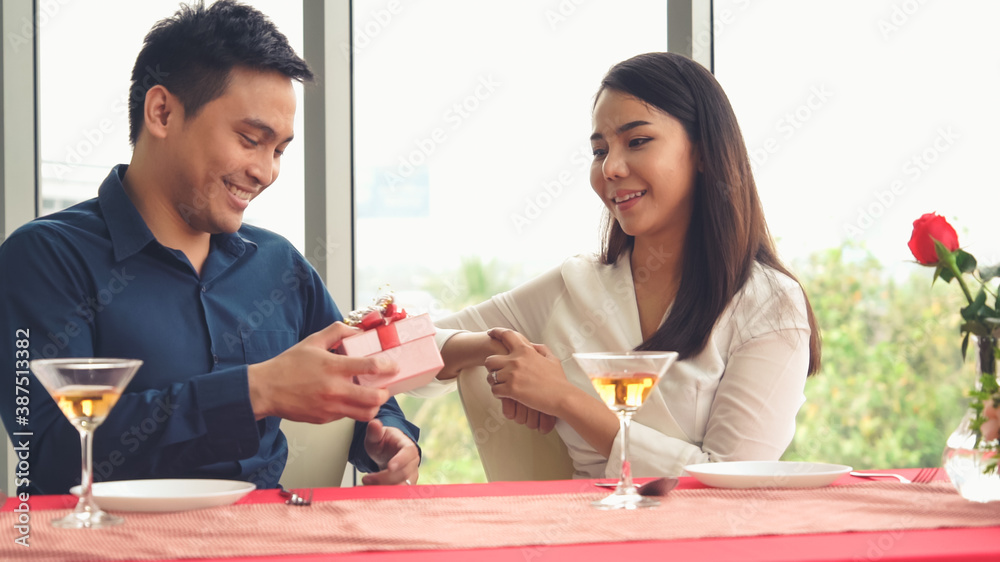 Romantic couple giving gift to lover at restaurant . Happy couple lifestyle .