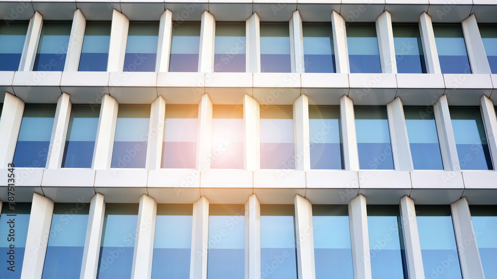 Blue curtain wall made of toned glass and steel constructions under blue sky. A fragment of a buildi