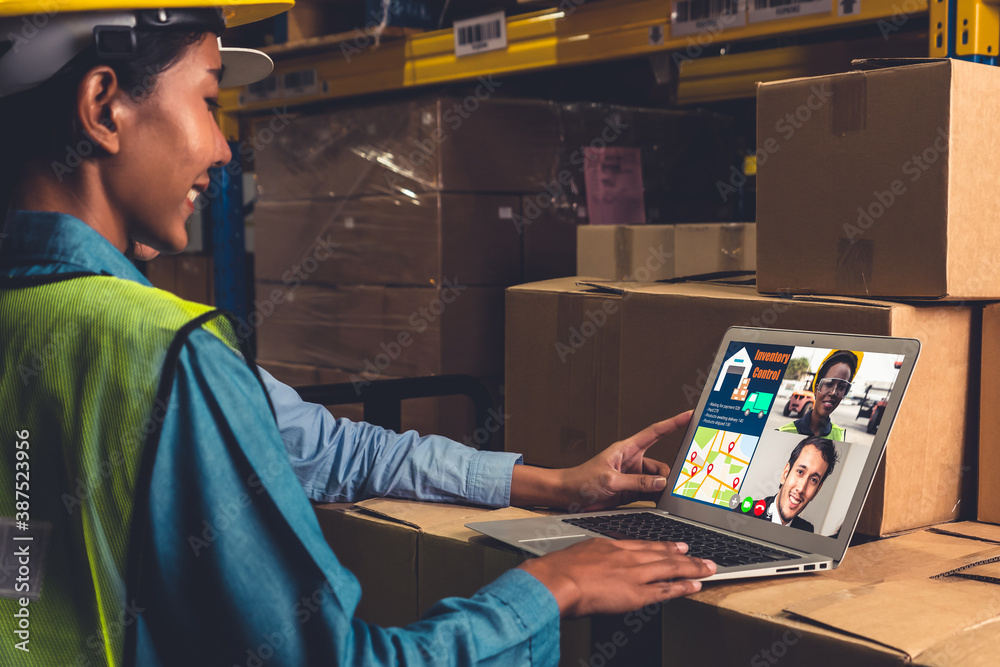 Warehouse staff talking on video call at computer screen in storage warehouse . Online software tech