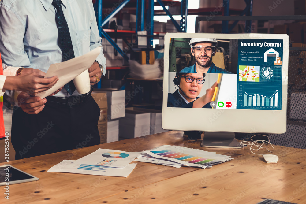 Warehouse staff talking on video call at computer screen in storage warehouse . Online software tech