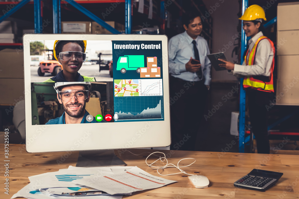 Warehouse staff talking on video call at computer screen in storage warehouse . Online software tech