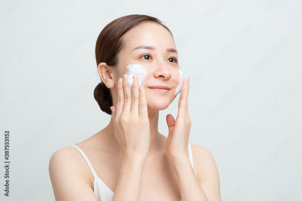 Face skin care. Woman applying facial cleanser on face closeup. Girl using cleansing cosmetic produc