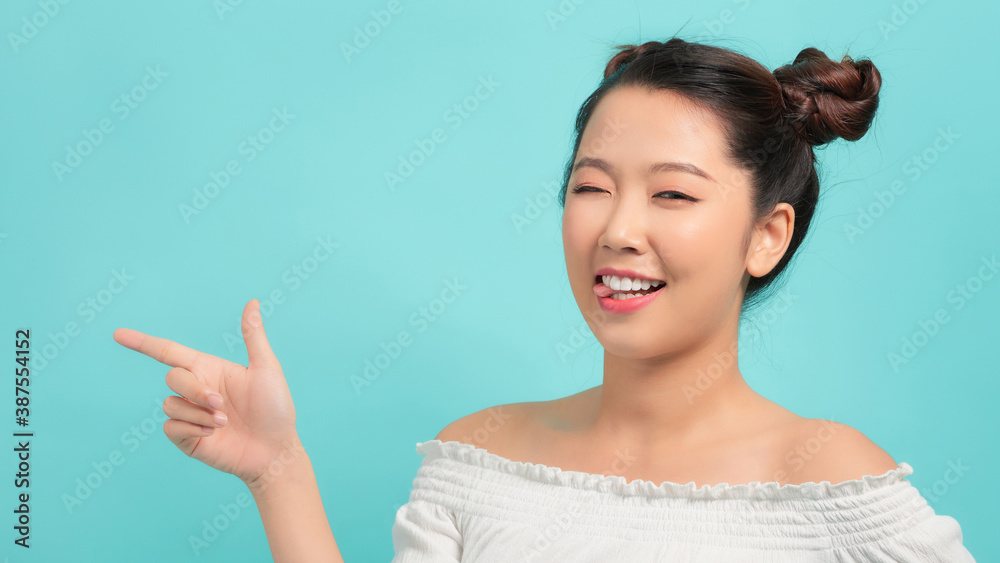 Young woman winks and point at side