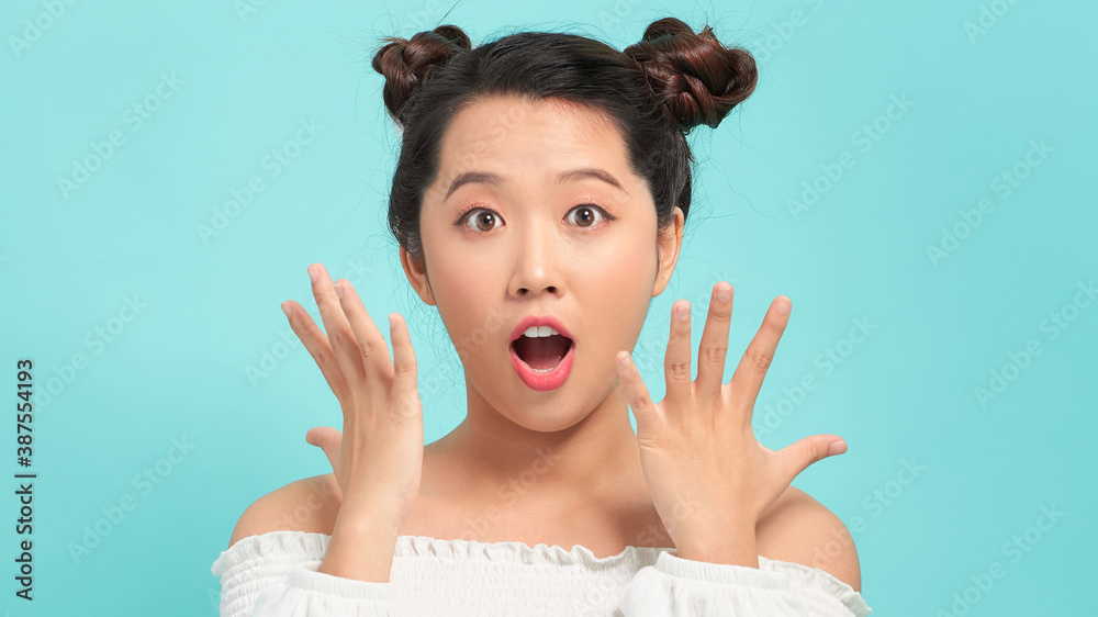 Surprised happy beautiful woman looking sideways in excitement. Isolated on blue background