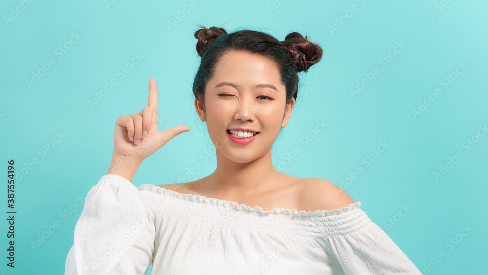 Young woman winks and point at side