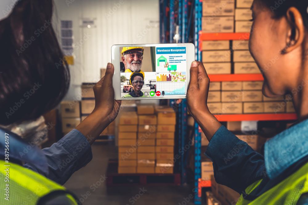 Warehouse staff talking on video call at computer screen in storage warehouse . Online software tech