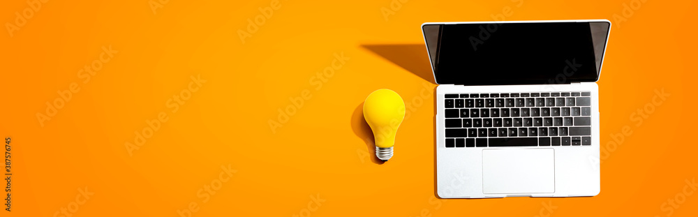 Laptop computer with a yellow light bulb from above