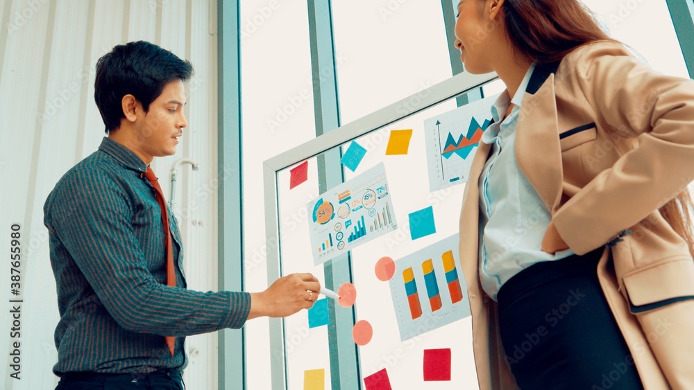 Business people work on project planning board in office and having conversation with coworker frien