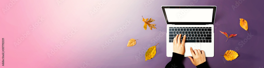 Autumn leaves with person using a laptop computer from above