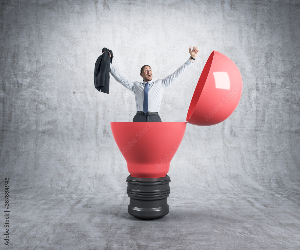 Happy businessman sitting in a big red light bulb